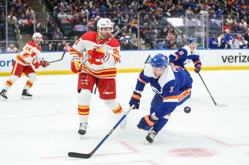 Feb 10, 2024; Elmont, New York, USA;  Calgary Flames center Nazem Kadri (91) and New York Islanders defenseman Adam Pelech (3) battle for control of the puck in the second period at UBS Arena. Mandatory Credit: Wendell Cruz-USA TODAY Sports