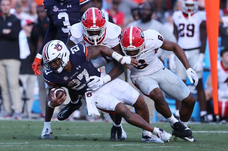 Sep 30, 2023; Auburn, Alabama, USA;  Auburn Tigers running back Jarquez Hunter (27) is tackled by Georgia Bulldogs linebacker C.J. Allen (33) and defensive back Daylen Everette (6) during the third quarter at Jordan-Hare Stadium. Mandatory Credit: John Reed-USA TODAY Sports