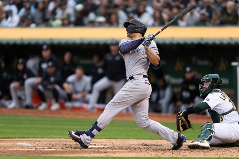 Jun 28, 2023; Oakland, California, USA;  New York Yankees designated hitter Giancarlo Stanton (27) hits a solo home run during the fourth inning against the Oakland Athletics at Oakland-Alameda County Coliseum. Mandatory Credit: Stan Szeto-USA TODAY Sports