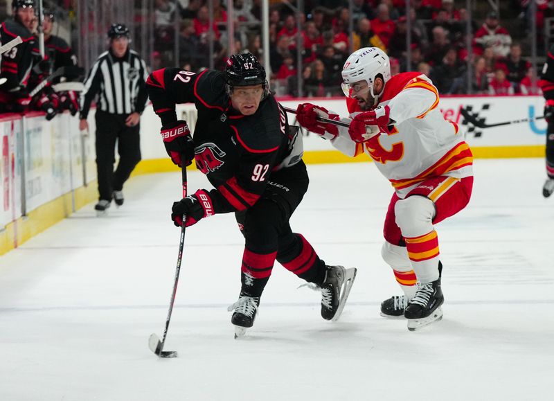 Mar 10, 2024; Raleigh, North Carolina, USA;  Carolina Hurricanes center Evgeny Kuznetsov (92) tries to control the puck against Calgary Flames right wing Matt Coronato (27) at PNC Arena. Mandatory Credit: James Guillory-USA TODAY Sports