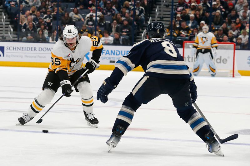 Nov 15, 2024; Columbus, Ohio, USA; Pittsburgh Penguins defenseman Erik Karlsson (65) carries the puck as Columbus Blue Jackets defenseman Zach Werenski (8) defends during the third period at Nationwide Arena. Mandatory Credit: Russell LaBounty-Imagn Images