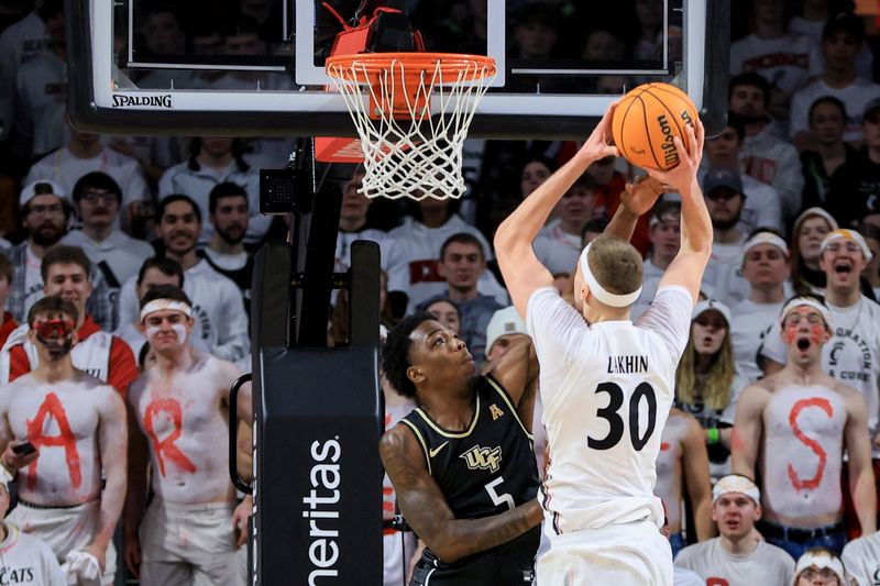 Feb 4, 2023; Cincinnati, Ohio, USA;  Cincinnati Bearcats forward Viktor Lakhin (30) drives to the basket as he fouled by UCF Knights guard P.J. Edwards (5) in the second half at Fifth Third Arena. Mandatory Credit: Aaron Doster-USA TODAY Sports