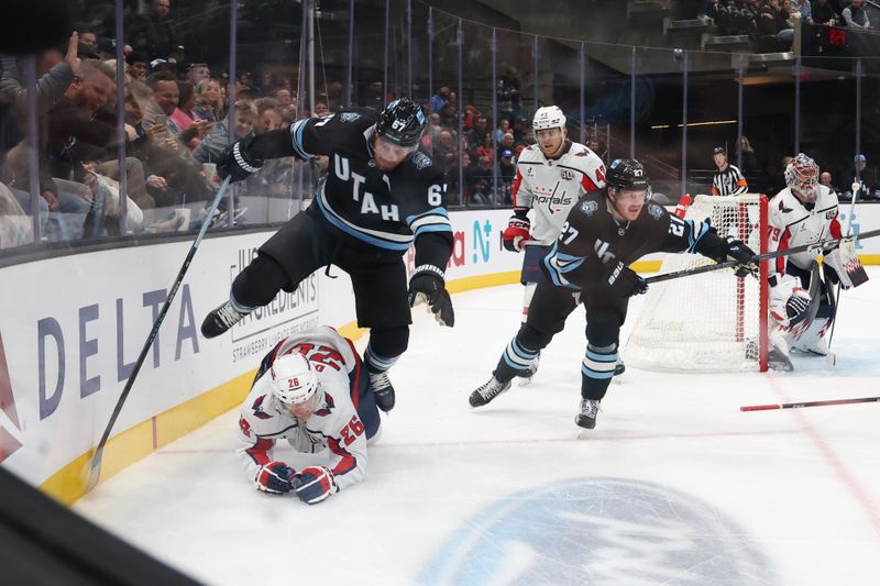 Nov 18, 2024; Salt Lake City, Utah, USA; Utah Hockey Club left wing Lawson Crouse (67) leaps over Washington Capitals center Nic Dowd (26) during the second period at Delta Center. Mandatory Credit: Rob Gray-Imagn Images