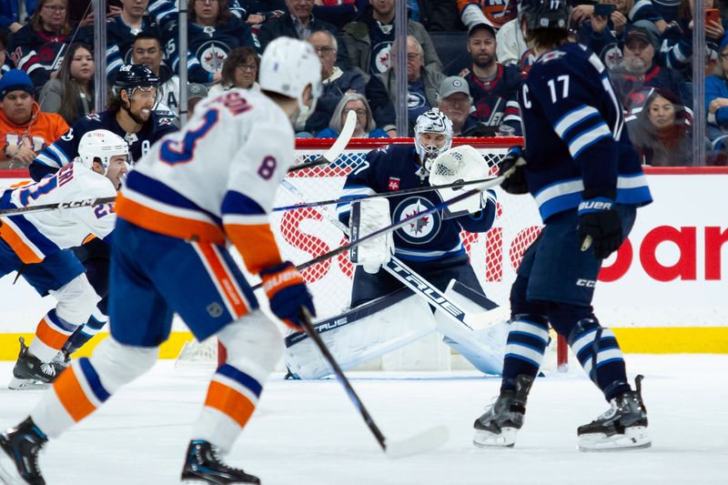 Jan 16, 2024; Winnipeg, Manitoba, CAN; Winnipeg Jets goalie Connor Hellebuyck (37) makes a save on a shot by New York Islanders defenseman Noah Dobson (8) during the second period at Canada Life Centre. Mandatory Credit: Terrence Lee-USA TODAY Sports