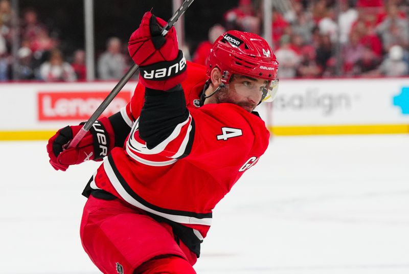 Apr 2, 2025; Raleigh, North Carolina, USA;  Carolina Hurricanes defenseman Shayne Gostisbehere (4) shoots against the Washington Capitals during the third period at Lenovo Center. Mandatory Credit: James Guillory-Imagn Images