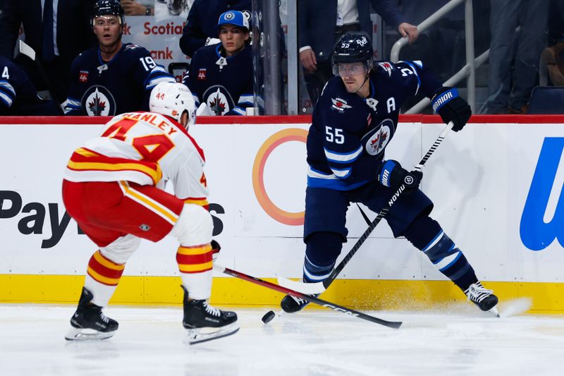 Sep 27, 2025; Winnipeg, Manitoba, CAN;  Winnipeg Jets forward Mark Scheifele (55) makes a pass by Calgary Flames defenseman Joel Hamley (44) during the second period at Canada Life Centre. Mandatory Credit: Terrence Lee-Imagn Images