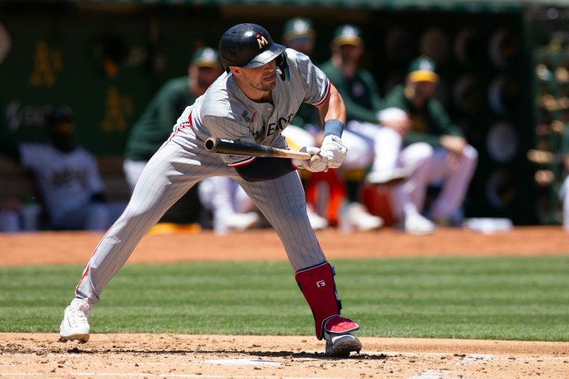 Jun 22, 2024; Oakland, California, USA; Minnesota Twins second baseman Kyle Farmer (12) is hit by a pitch from Oakland Athletics starting pitcher JP Sears during the second inning at Oakland-Alameda County Coliseum. Mandatory Credit: D. Ross Cameron-USA TODAY Sports