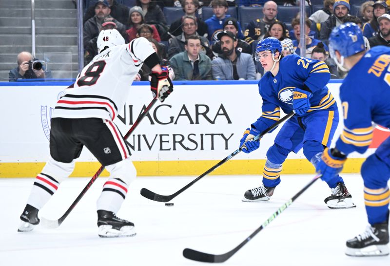 Nov 21, 2025; Buffalo, New York, USA; Buffalo Sabres right wing Jack Quinn (22) tries to move the puck past Chicago Blackhawks defenseman Matt Grzelcyk (48) in the second period at KeyBank Center. Mandatory Credit: Mark Konezny-Imagn Images