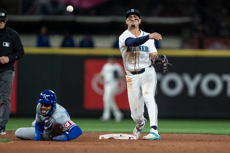 May 13, 2024; Seattle, Washington, USA; Seattle Mariners second baseman Josh Rojas (4) attempts to turn a double play after forcing out Kansas City Royals third baseman Maikel Garcia (11) at second base during the eighth inning at T-Mobile Park. Mandatory Credit: Stephen Brashear-USA TODAY Sports