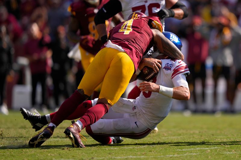 New York Giants quarterback Daniel Jones (8) is hit by Washington Commanders linebacker Frankie Luvu (4) during the second half of an NFL football game in Landover, Md., Sunday, Sept. 15, 2024. (AP Photo/Matt Slocum)