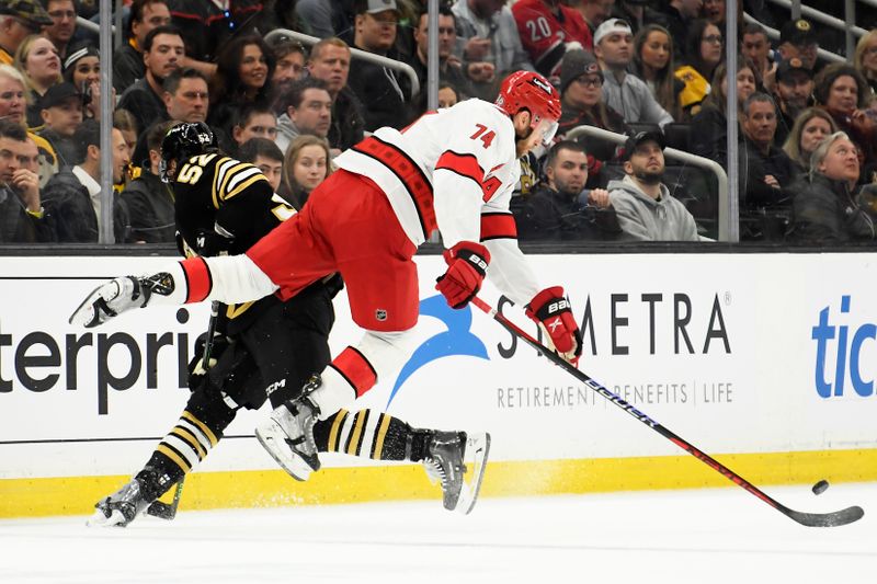 Apr 9, 2024; Boston, Massachusetts, USA; Boston Bruins defenseman Andrew Peeke (52) checks Carolina Hurricanes defenseman Jaccob Slavin (74) during the first period at TD Garden. Mandatory Credit: Bob DeChiara-USA TODAY Sports