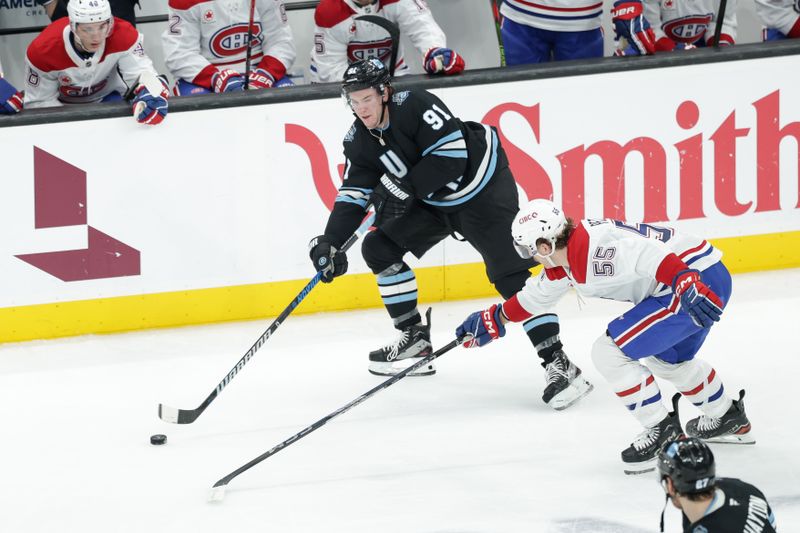 Jan 14, 2025; Salt Lake City, Utah, USA;  Utah Hockey Club right wing Josh Doan (91) passes the puck past the stick of Montreal Canadiens left wing Michael Pezzetta (55) during the second period at Delta Center. Mandatory Credit: Chris Nicoll-Imagn Images