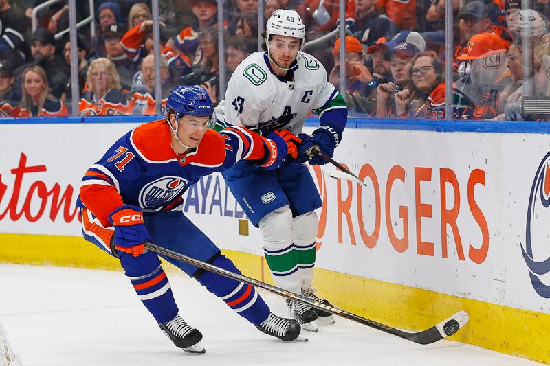 Apr 13, 2024; Edmonton, Alberta, CAN; Edmonton Oilers forward Ryan McLeod (71) protects the puck from Vancouver Canucks defensemen Quinn Hughes (43) during the first period at Rogers Place. Mandatory Credit: Perry Nelson-USA TODAY Sports