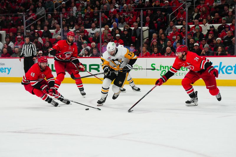 Jan 13, 2024; Raleigh, North Carolina, USA;  Pittsburgh Penguins right wing Bryan Rust (17) is stopped with the puck by Carolina Hurricanes left wing Jordan Martinook (48) and defenseman Jaccob Slavin (74) during the second period at PNC Arena. Mandatory Credit: James Guillory-USA TODAY Sports