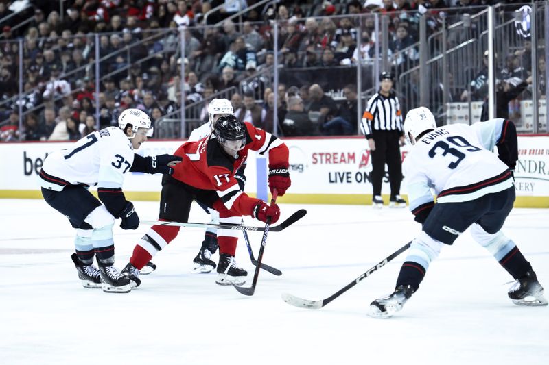 Feb 12, 2024; Newark, New Jersey, USA; New Jersey Devils defenseman Simon Nemec (17) passes the puck as Seattle Kraken center Yanni Gourde (37) and 
defenseman Ryker Evans (39) defend during the second period at Prudential Center. Mandatory Credit: John Jones-USA TODAY Sports