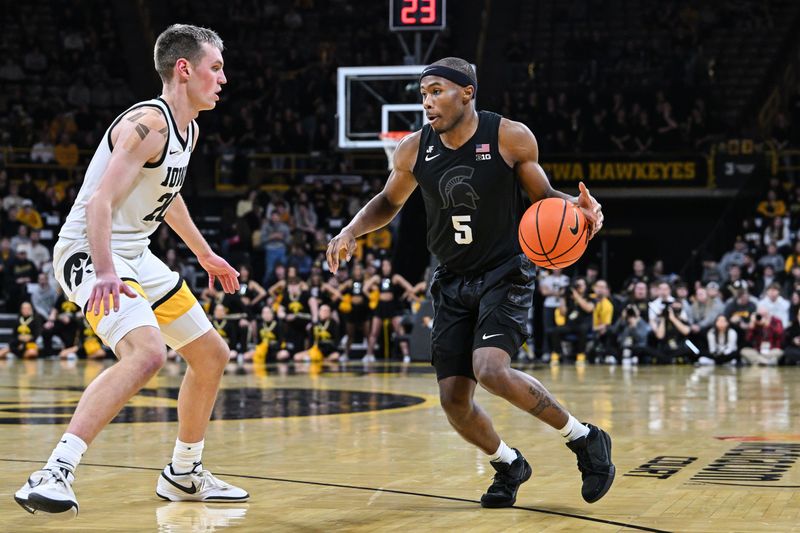 Mar 6, 2025; Iowa City, Iowa, USA; Michigan State Spartans guard Tre Holloman (5) controls the ball as Iowa Hawkeyes forward Payton Sandfort (20) defends during the first half at Carver-Hawkeye Arena. Mandatory Credit: Jeffrey Becker-Imagn Images