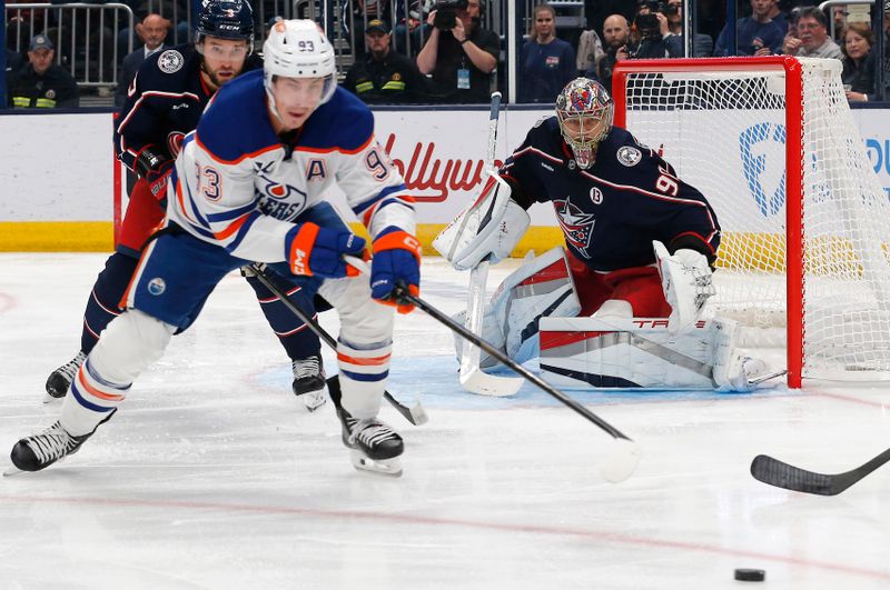 Oct 28, 2024; Columbus, Ohio, USA; Columbus Blue Jackets goalie Elvis Merzlikins (90) looks on as Edmonton Oilers center Ryan Nugent-Hopkins (93) reaches for a loose puck during the first period at Nationwide Arena. Mandatory Credit: Russell LaBounty-Imagn Images