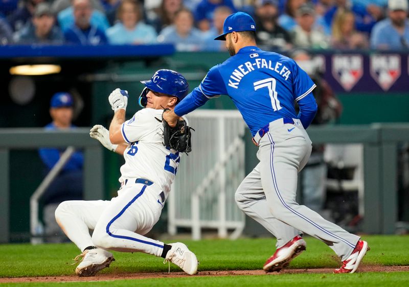 Apr 23, 2024; Kansas City, Missouri, USA; Kansas City Royals designated hitter Adam Frazier (26) is caught in a rundown by Toronto Blue Jays third base Isiah Kiner-Falefa (7) during the fifth inning at Kauffman Stadium. Mandatory Credit: Jay Biggerstaff-USA TODAY Sports