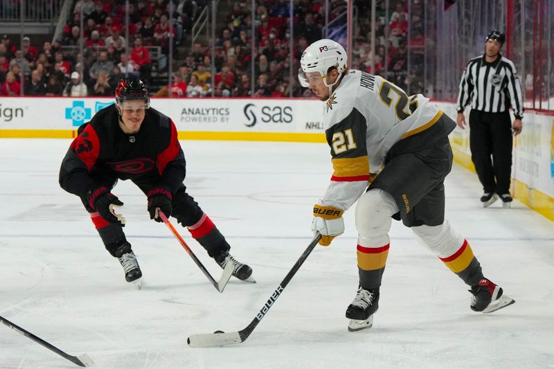 Mar 11, 2023; Raleigh, North Carolina, USA;  Vegas Golden Knights center Brett Howden (21) holds onto the puck against Carolina Hurricanes right wing Jesse Puljujarvi (13) during the second period at PNC Arena. Mandatory Credit: James Guillory-USA TODAY Sports