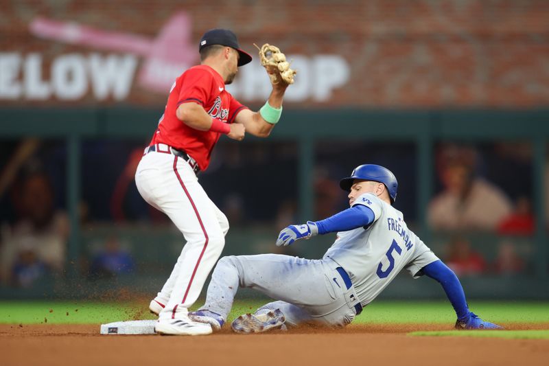 Sep 13, 2024; Atlanta, Georgia, USA; Los Angeles Dodgers first baseman Freddie Freeman (5) slides safely into second with a stolen base before the tag attempt of Atlanta Braves second baseman Whit Merrifield (15) in the first inning at Truist Park. Mandatory Credit: Brett Davis-Imagn Images