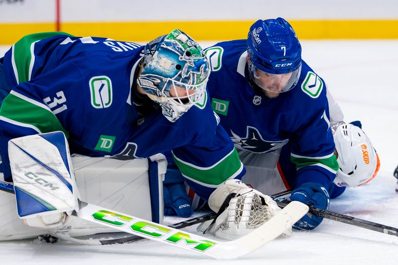 Oct 4, 2024; Vancouver, British Columbia, CAN; Vancouver Canucks goalie Arturs Silovs (31) and defenseman Carson Soucy (7) cover the puck as Edmonton Oilers forward Corey Perry (90) lays on the ice during the second period at Rogers Arena. Mandatory Credit: Bob Frid-Imagn Images