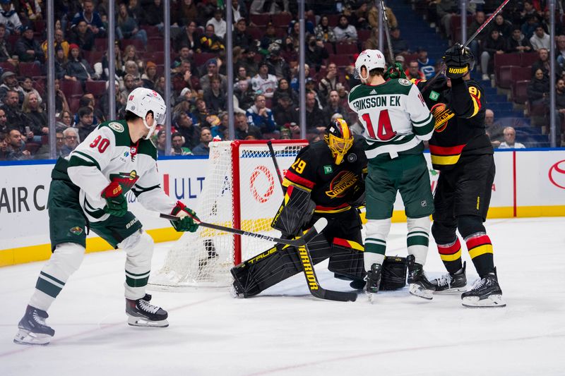 Dec 7, 2023; Vancouver, British Columbia, CAN; Vancouver Canucks goalie Casey DeSmith (29) makes a save as forward Dakota Joshua (81) battles with Minnesota Wild forward Joel Eriksson Ek (14) while forward Marcus Johansson (90) looks on in the second period at Rogers Arena. Mandatory Credit: Bob Frid-USA TODAY Sports