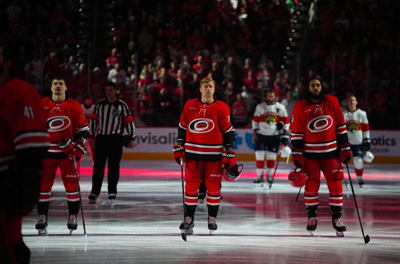 Nov 29, 2024; Raleigh, North Carolina, USA;  Carolina Hurricanes defenseman Dmitry Orlov (7) center Jack Drury (18) and defenseman Jalen Chatfield (5) looks on before the start of the game against the Florida Panthers at Lenovo Center. Mandatory Credit: James Guillory-Imagn Images