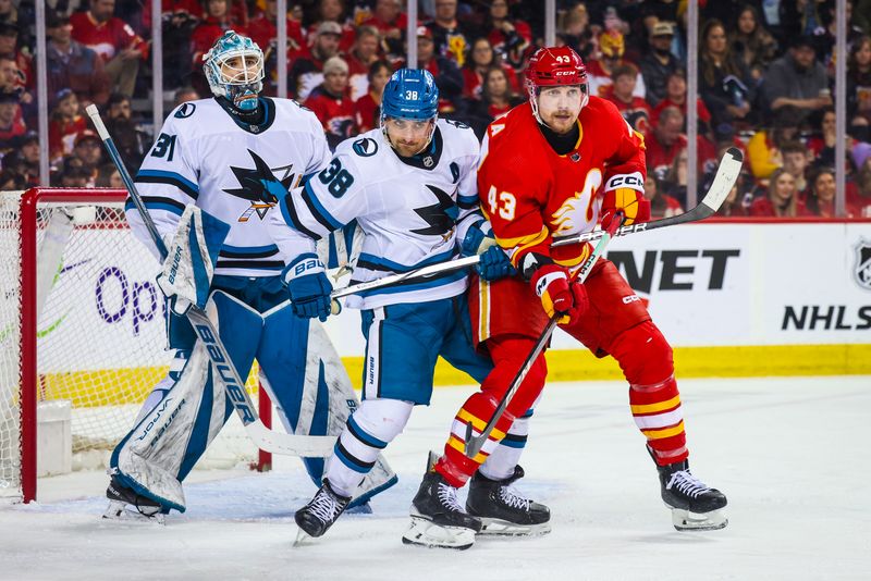 Apr 18, 2024; Calgary, Alberta, CAN; Calgary Flames right wing Adam Klapka (43) and San Jose Sharks defenseman Mario Ferraro (38) battles for the puck in front of San Jose Sharks goaltender Georgi Romanov (31) during the second period at Scotiabank Saddledome. Mandatory Credit: Sergei Belski-USA TODAY Sports