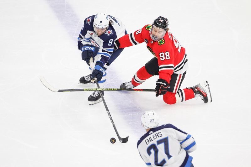 Feb 23, 2024; Chicago, Illinois, USA; Winnipeg Jets left wing Alex Iafallo (9) battles for the puck with Chicago Blackhawks center Connor Bedard (98) during the first period at United Center. Mandatory Credit: Kamil Krzaczynski-USA TODAY Sports