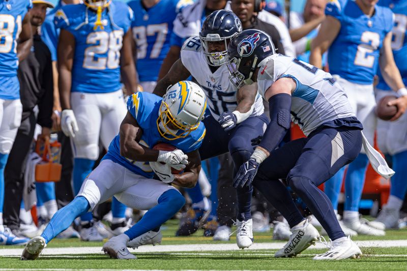 Los Angeles Chargers wide receiver Derius Davis (12) leans for yardage as he's tackled by Tennessee Titans running back Julius Chestnut (36) and Tennessee Titans defensive tackle Shakel Brown (91) on a kick return during their NFL football game Sunday, Sept. 17, 2023, in Nashville, Tenn. (AP Photo/Wade Payne)