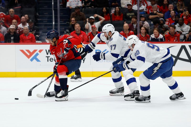 Oct 14, 2025; Washington, District of Columbia, USA; Washington Capitals right wing Justin Sourdif (34) skates with the puck as Tampa Bay Lightning defenseman Victor Hedman (77) and Lightning defenseman J.J. Moser (90) chase in the first period at Capital One Arena. Mandatory Credit: Geoff Burke-Imagn Images
