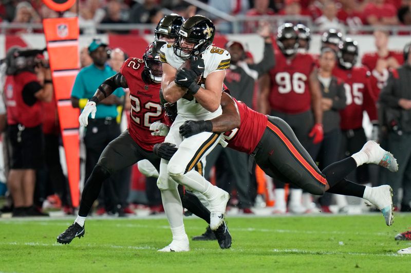 New Orleans Saints tight end Adam Trautman is stopped by Tampa Bay Buccaneers defensive end William Gholston (92) and safety Keanu Neal (22) on a pass reception in the second half of an NFL football game in Tampa, Fla., Monday, Dec. 5, 2022. (AP Photo/Chris O'Meara)
