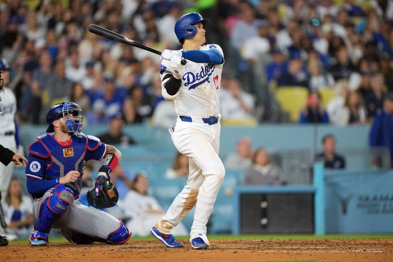 Jun 11, 2024; Los Angeles, California, USA; Los Angeles Dodgers designated hitter Shohei Ohtani (17) hits a two-run home run in the sixth inning as Texas Rangers catcher Jonah Heim (28) watches at Dodger Stadium. Mandatory Credit: Kirby Lee-USA TODAY Sports
