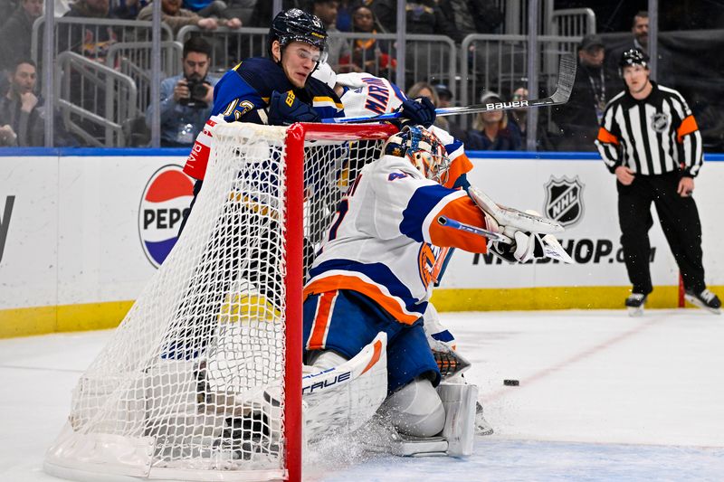 Feb 22, 2024; St. Louis, Missouri, USA;  St. Louis Blues right wing Alexey Toropchenko (13) is checked into the net as he shoots against New York Islanders goaltender Semyon Varlamov (40) during the second period at Enterprise Center. Mandatory Credit: Jeff Curry-USA TODAY Sports