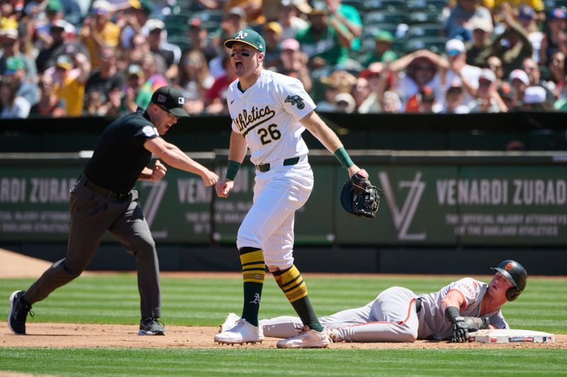 Aug 18, 2024; Oakland, California, USA; Oakland Athletics infielder Tyler Nevin (26) reacts after tagging out San Francisco Giants infielder Tyler Fitzgerald (49) at first base as umpire Chris Segal (96) makes the call during the fourth inning at Oakland-Alameda County Coliseum. Mandatory Credit: Robert Edwards-USA TODAY Sports