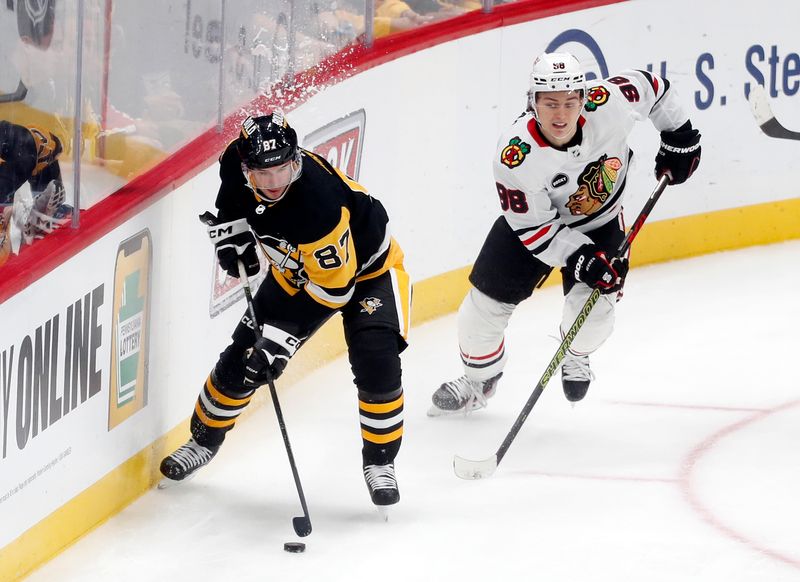 Oct 10, 2023; Pittsburgh, Pennsylvania, USA; Pittsburgh Penguins center Sidney Crosby (87) moves the puck ahead of Chicago Blackhawks center Connor Bedard (98) during the second period at the PPG Paints Arena. Chicago won 4-2. Mandatory Credit: Charles LeClaire-USA TODAY Sports