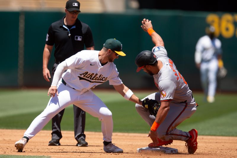 Jul 7, 2024; Oakland, California, USA; Baltimore Orioles right fielder Anthony Santander (25) slides safely into second base with a steal ahead of the tag by Oakland Athletics shortstop Max Schuemann (12) during the third inning at Oakland-Alameda County Coliseum. Umpire is Brennan Miller. Mandatory Credit: D. Ross Cameron-USA TODAY Sports