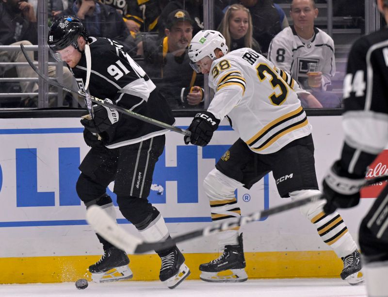 Oct 21, 2023; Los Angeles, California, USA; Los Angeles Kings right wing Carl Grundstrom (91) controls the puck against Boston Bruins center Patrick Brown (38) during the first period at Crypto.com Arena. Mandatory Credit: Alex Gallardo-USA TODAY Sports