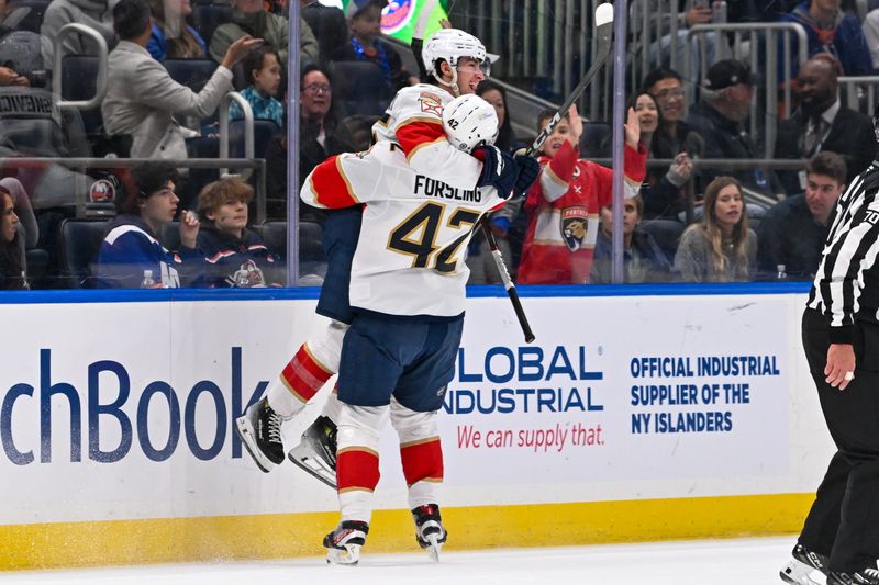 Oct 26, 2024; Elmont, New York, USA;  Florida Panthers right wing Mackie Samoskevich (25) celebrates his goal with Florida Panthers defenseman Gustav Forsling (42)] against the New York Islanders during the second period at UBS Arena. Mandatory Credit: Dennis Schneidler-Imagn Images