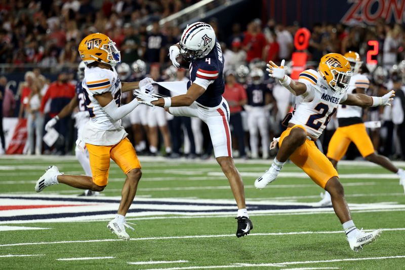 Sep 16, 2023; Tucson, Arizona, USA; Arizona Wildcats wide receiver Tetairoa McMillan (4) makes a catch against UTEP Miners cornerback Ilijah Johnson (32) and defensive back McKel Broussard (24) during the first half at Arizona Stadium. Mandatory Credit: Zachary BonDurant-USA TODAY Sports