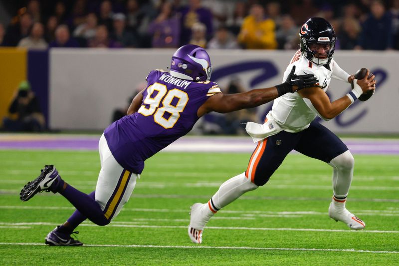 Chicago Bears quarterback Justin Fields (1) runs from Minnesota Vikings linebacker D.J. Wonnum (98) during the first half of an NFL football game, Monday, Nov. 27, 2023, in Minneapolis. (AP Photo/Bruce Kluckhohn)