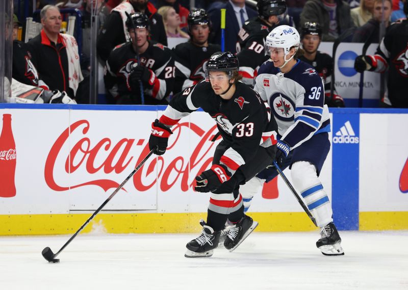 Mar 3, 2024; Buffalo, New York, USA;  Buffalo Sabres defenseman Ryan Johnson (33) controls the puck as Winnipeg Jets center Morgan Barron (36) defends during the first period at KeyBank Center. Mandatory Credit: Timothy T. Ludwig-USA TODAY Sports