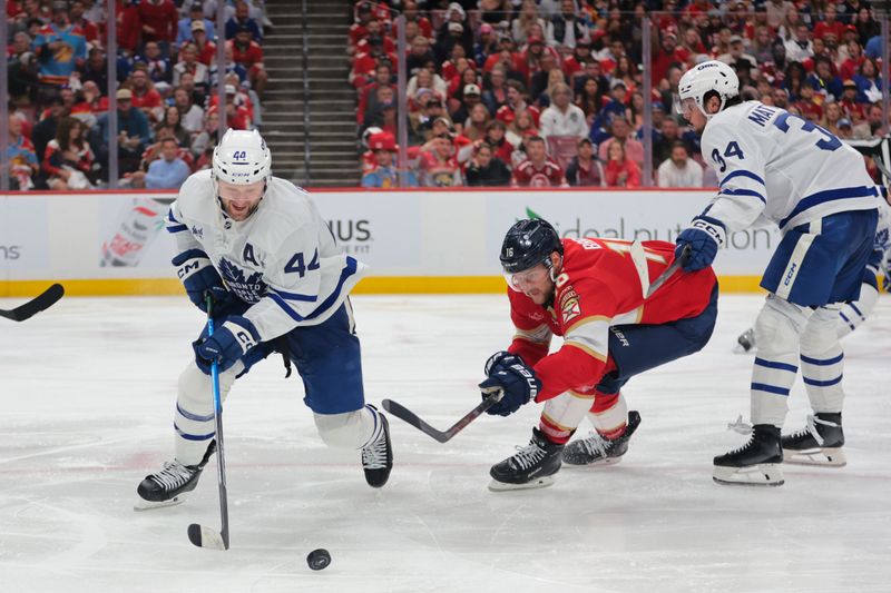 May 9, 2025; Sunrise, Florida, USA; Toronto Maple Leafs defenseman Morgan Rielly (44) moves the puck past Florida Panthers center Aleksander Barkov (16) during overtime in game three of the second round of the 2025 Stanley Cup Playoffs at Amerant Bank Arena. Mandatory Credit: Sam Navarro-Imagn Images