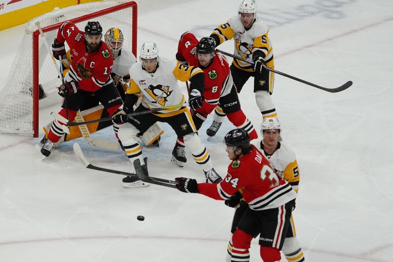 Dec 28, 2025; Chicago, Illinois, USA; Pittsburgh Penguins defenseman Jack St. Ivany (3) and Chicago Blackhawks center Colton Dach (34) battle for the puck during the first period at United Center. Mandatory Credit: David Banks-Imagn Images