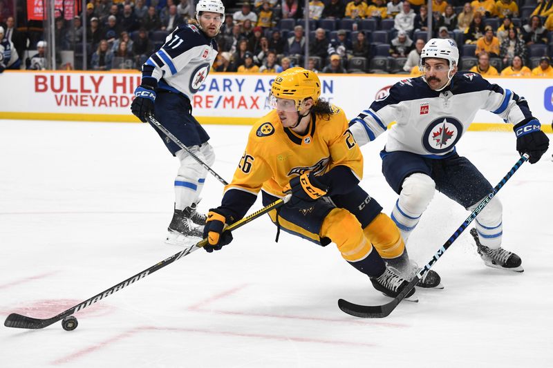 Nov 26, 2023; Nashville, Tennessee, USA; Nashville Predators center Philip Tomasino (26) handles the puck against Winnipeg Jets defenseman Dylan DeMelo (2) during the third period at Bridgestone Arena. Mandatory Credit: Christopher Hanewinckel-USA TODAY Sports