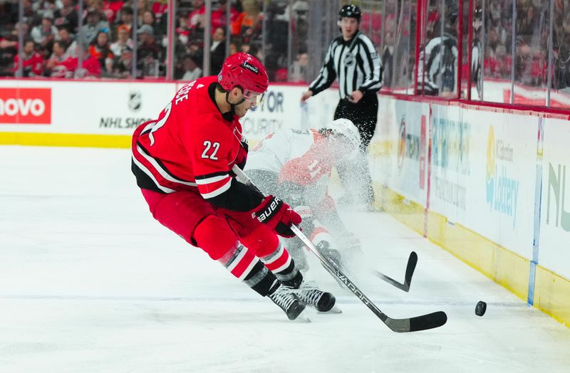 Mar 21, 2024; Raleigh, North Carolina, USA; Carolina Hurricanes defenseman Brett Pesce (22) gets to the puck ahead of Philadelphia Flyers right wing Travis Konecny (11) during the second period at PNC Arena. Mandatory Credit: James Guillory-USA TODAY Sports