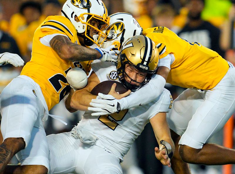 Sep 21, 2024; Columbia, Missouri, USA; Vanderbilt Commodores quarterback Diego Pavia (2) is tackled by Missouri Tigers safety Joseph Charleston (28) and safety Marvin Burks Jr. (1) during overtime at Faurot Field at Memorial Stadium. Mandatory Credit: Jay Biggerstaff-Imagn Images