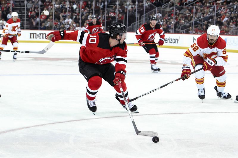 Feb 8, 2024; Newark, New Jersey, USA; New Jersey Devils right wing Alexander Holtz (10) skates with the puck while being defended by Calgary Flames defenseman MacKenzie Weegar (52) during the second period at Prudential Center. Mandatory Credit: John Jones-USA TODAY Sports