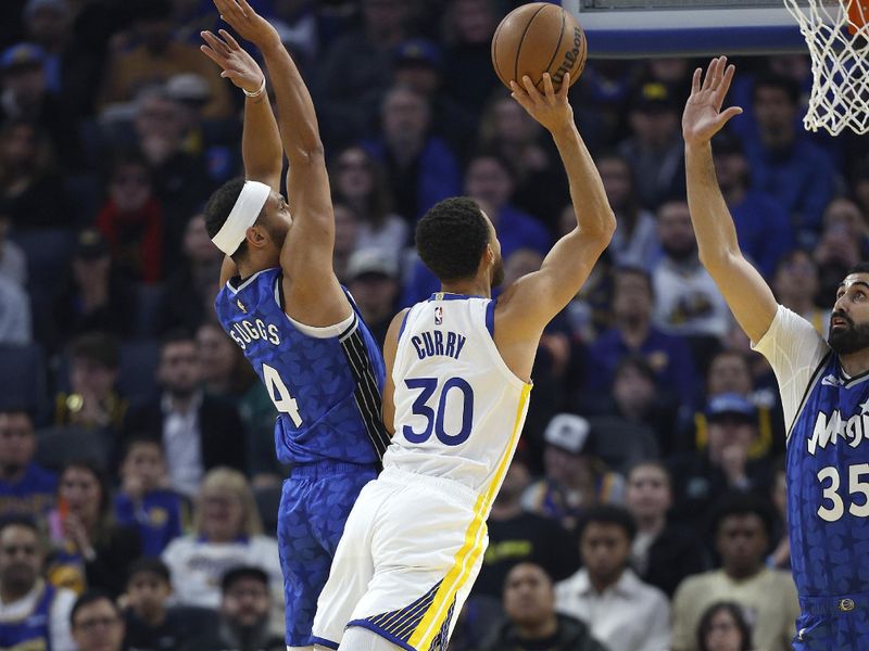 SAN FRANCISCO, CALIFORNIA - JANUARY 02: Stephen Curry #30 of the Golden State Warriors shoots over Jalen Suggs #4 and Goga Bitadze #35 of the Orlando Magic during the first quarter of an NBA basketball game at Chase Center on January 02, 2024 in San Francisco, California. NOTE TO USER: User expressly acknowledges and agrees that, by downloading and or using this photograph, User is consenting to the terms and conditions of the Getty Images License Agreement. (Photo by Thearon W. Henderson/Getty Images)