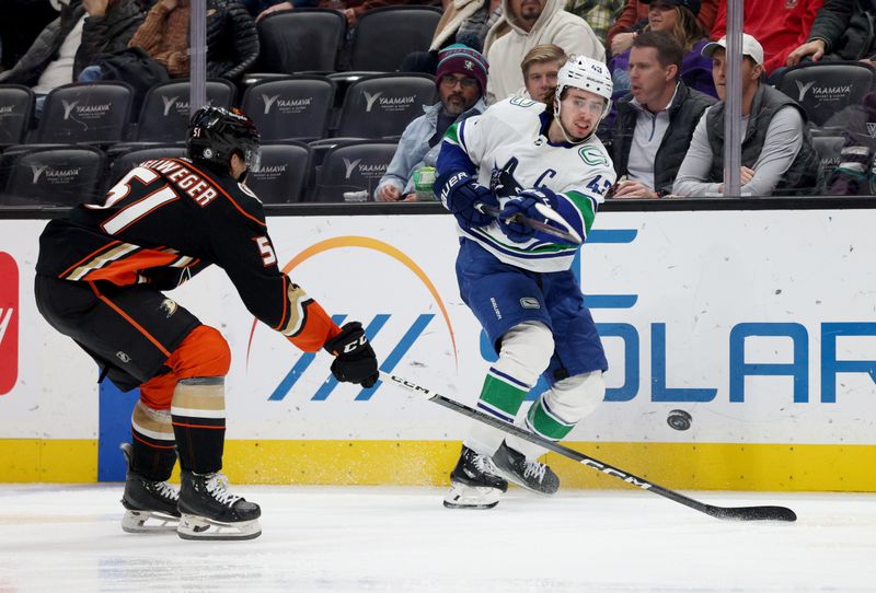 Mar 3, 2024; Anaheim, California, USA; Vancouver Canucks defenseman Quinn Hughes (43) passes against Anaheim Ducks defenseman Olen Zellweger (51) during the third period at Honda Center. Mandatory Credit: Jason Parkhurst-USA TODAY Sports